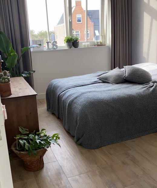 Slaapkamer in Noordwijk met lichte houtlook vloertegels en een tweepersoonsbed bij het raam