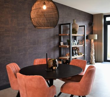 Eethoek in Noordwijk met grote lichte betonlook vloertegels, roze stoelen en een donkere wand