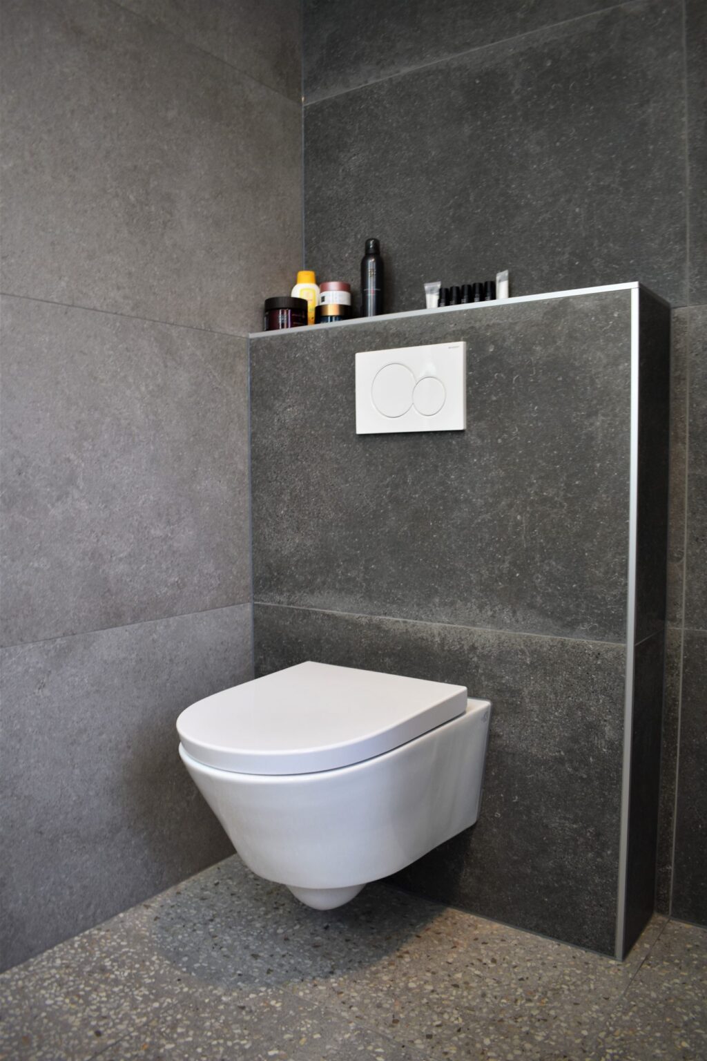 Toilet in Noordwijk met terrazzo look vloertegels en donkere betonlook wandtegels