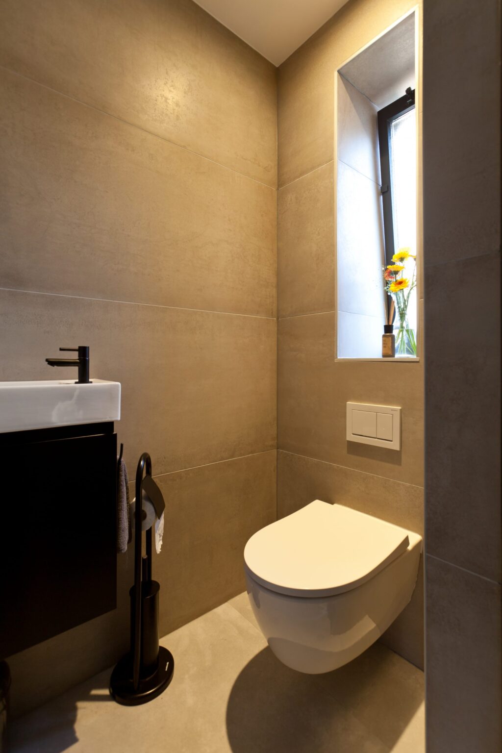 Toilet in Rijnsburg met grote metallook wandtegels, een fonteintje en een raam