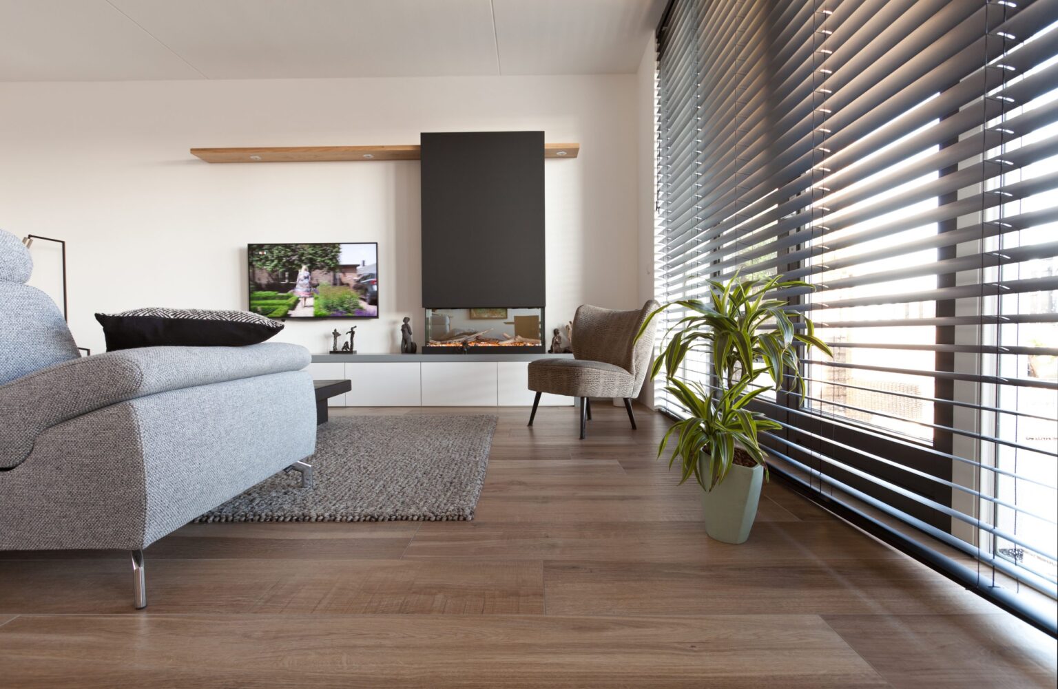 Woonkamer in een appartement in Noordwijk met warme houtlook vloertegels en een witte bank