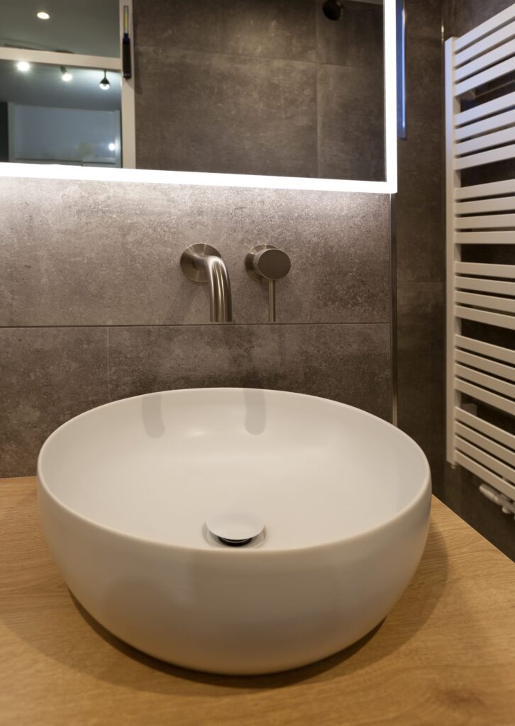 Witte opzetkom op een eiken blad tegen een wand met betonlook tegels van 100×100 in Katwijk