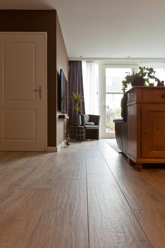 Woonkamer in Hillegom met warme houtlook vloertegels en antieke houten kasten