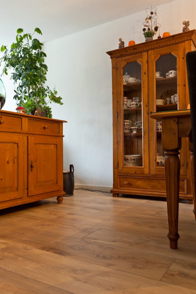 Woonkamer in Hillegom met warme houtlook vloertegels en een antieke houten vitrinekast