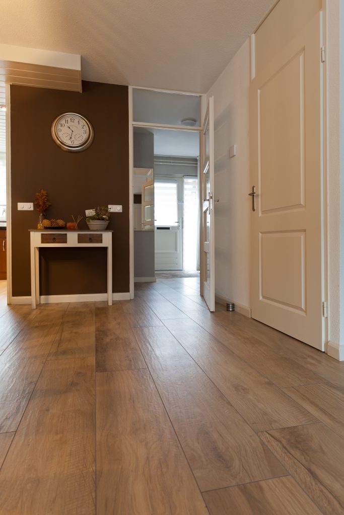 Woonkamer in Hillegom met warme houtlook vloertegels, een antieke kast en een klok aan de muur