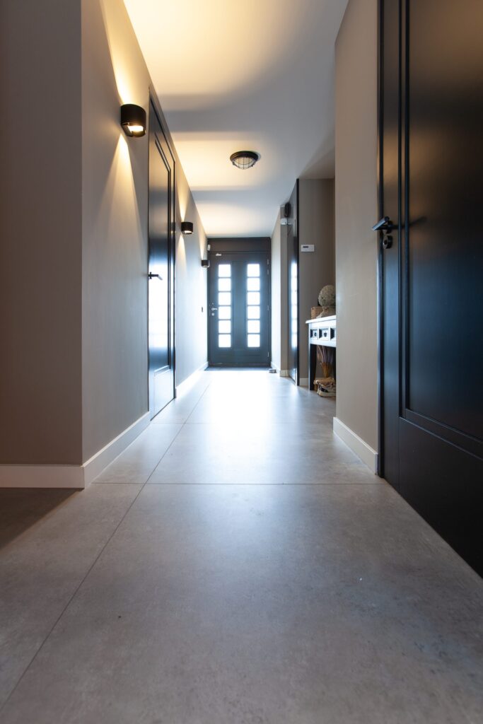 Lange hal in Noordwijk met grote lichtgrijze betonlook tegels van 100×100