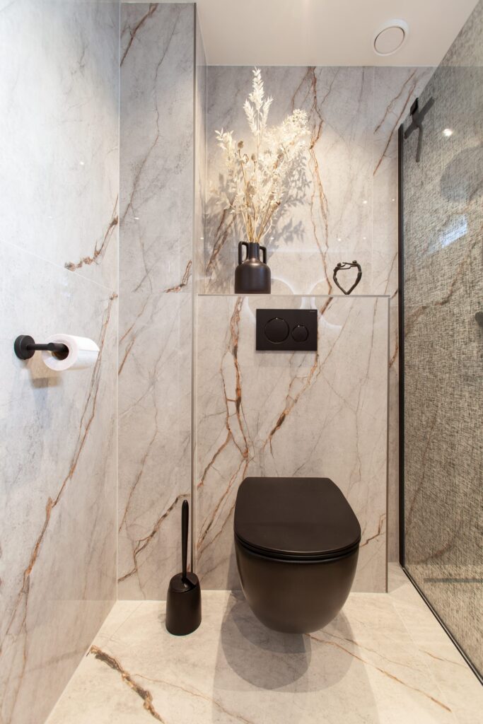 Toilet in Leiderdorp met witte marmerlook tegels en een zwart hangend toilet