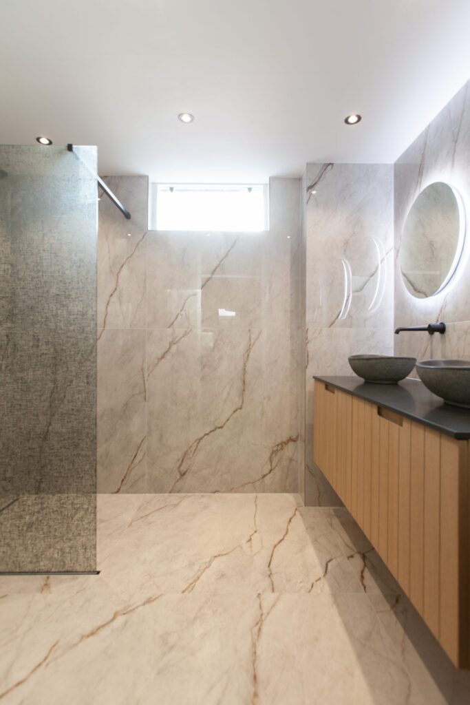 Badkamer in Leiderdorp met lichte natuursteenlook tegels, een inloopdouche en een houten badmeubel