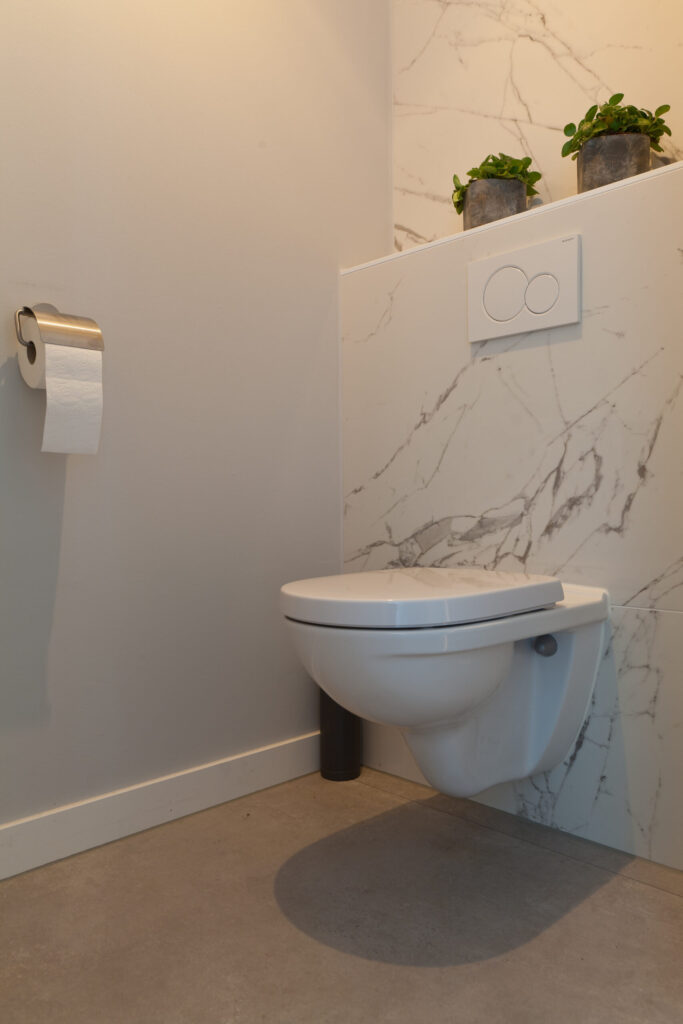 Toilet in Noordwijk met marmerlook wandtegels en betonlook vloertegels