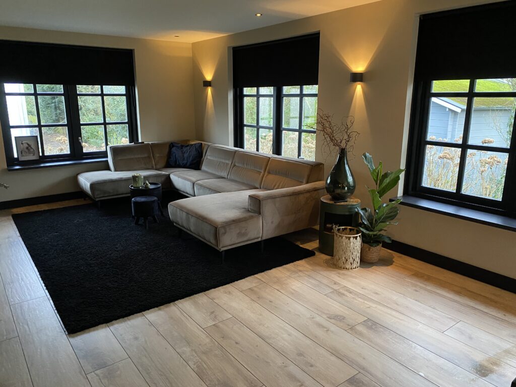 Woonkamer in Noordwijk met lichte houtlook tegels als keramisch parket en een hoekbank