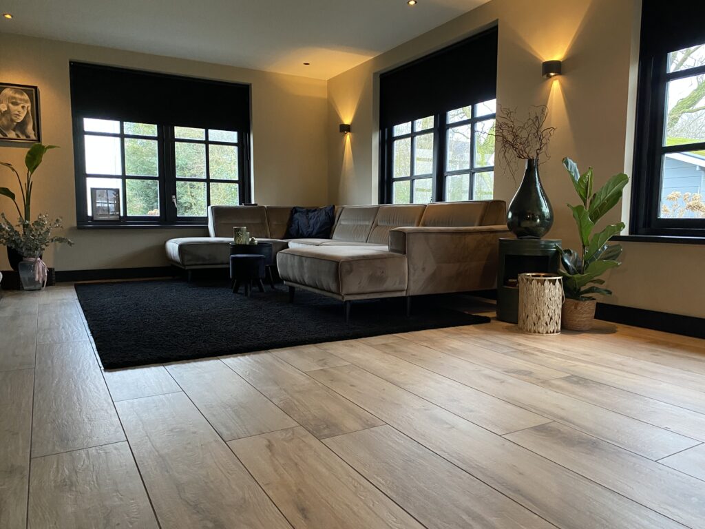 Woonkamer in Noordwijk met lichte houtlook tegels in keramisch parket en een zwart vloerkleed