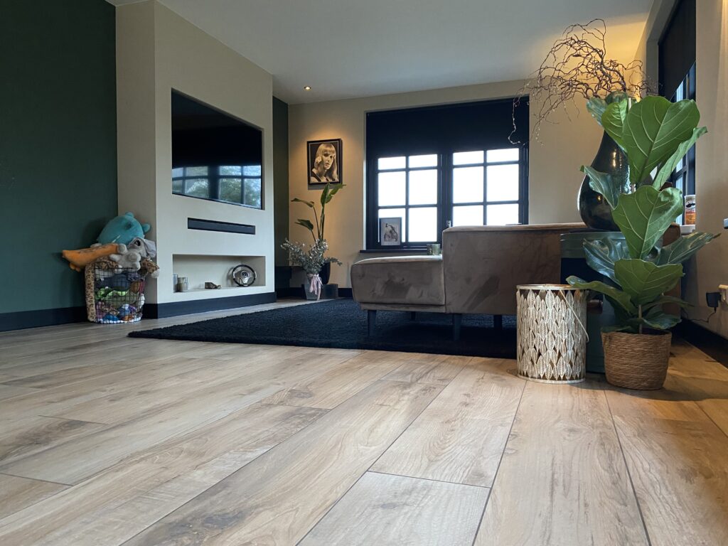 Woonkamer in Noordwijk met lichte houtlook tegels als keramisch parket en een tv-wand