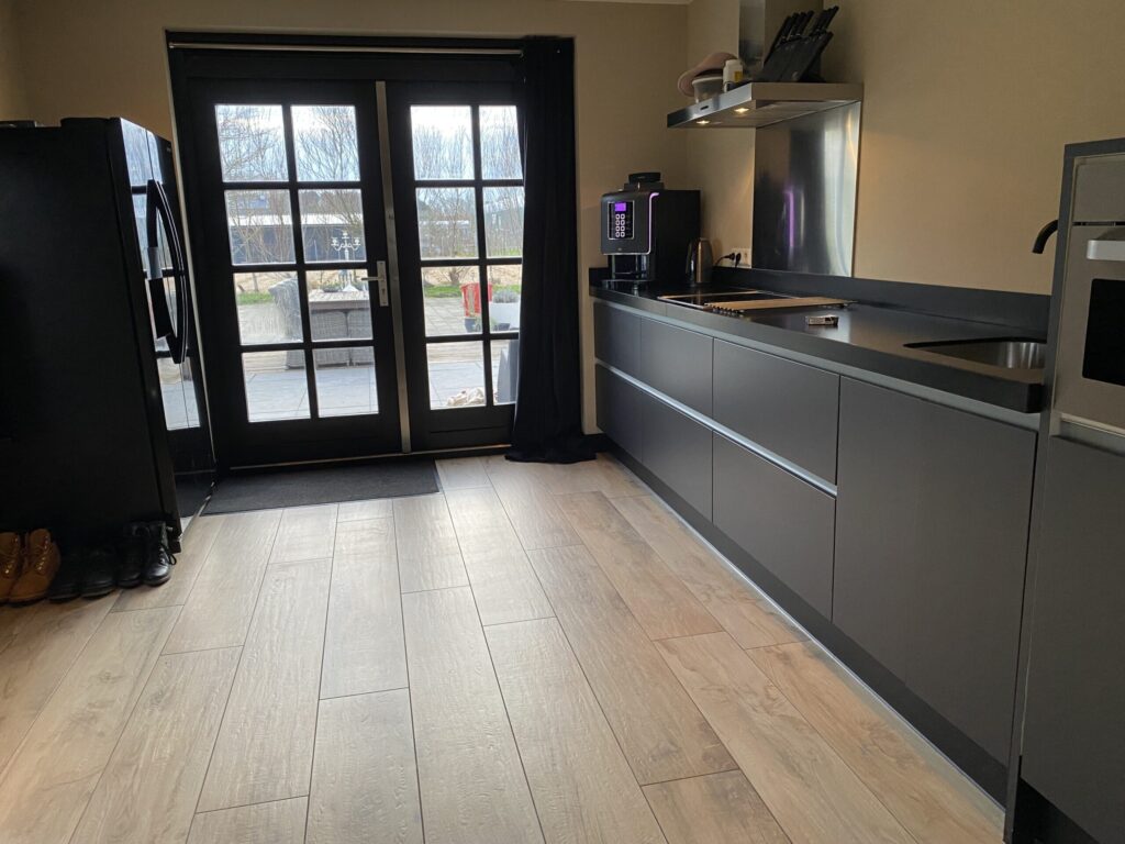 Lichte houtlook vloertegels in een keuken in Noordwijk met grijze keukenkasten