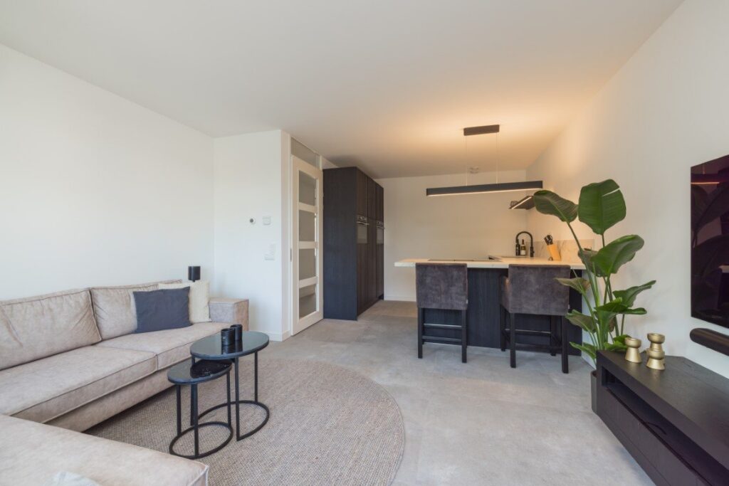 Open woonkamer en keuken in Leiden met een doorlopende vloer van grote betonlook tegels van 100×100