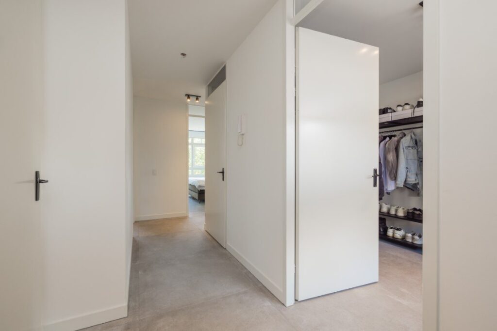 Hal van een appartement in Leiden met betonlook tegels van 100×100 die doorlopen tot in de inloopkast