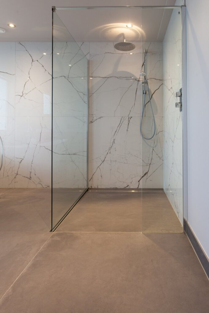 Inloopdouche met glazen wand en lijngoot in Warmond, met witte marmerlook tegels van 120×120 en een antraciet betonlook vloer