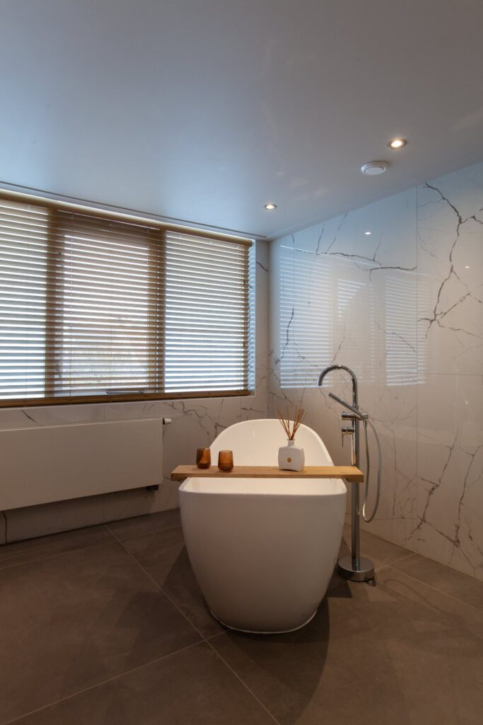 Vrijstaand bad voor een wand van witte glanzende marmerlook tegels van 120×120 met grijze aders in Warmond