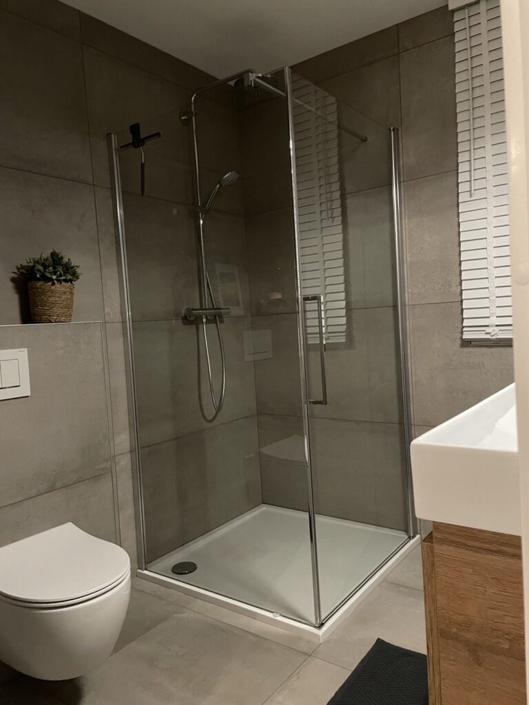 Badkamer in Voorschoten met metallook tegels van 60×120 op de wand, 60×60 op de vloer, een douchecabine en een hangend toilet