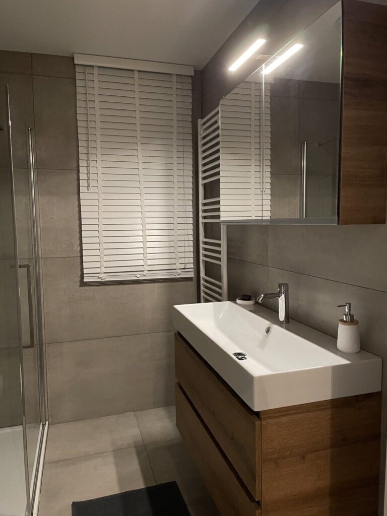 Wastafel met houten onderkast en spiegelkast voor een wand van metallook tegels van 60×120 in Voorschoten