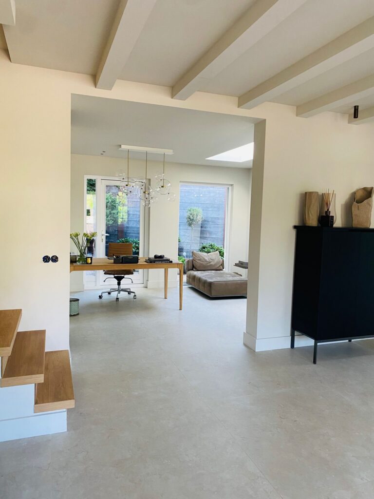 Lichte benedenverdieping in Wassenaar met beige natuursteenlook tegels van 120×120 en een doorkijk naar de tuinkamer
