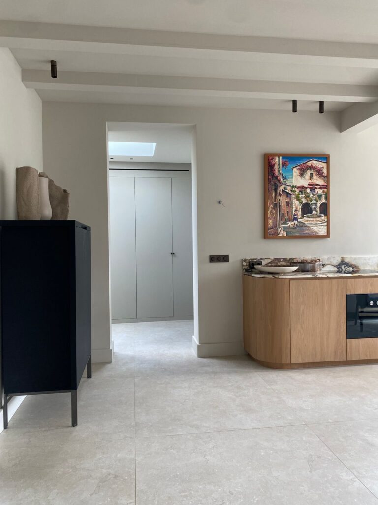Keuken met houten fronten en een doorgang naar de gang in Wassenaar, op beige natuursteenlook tegels van 120×120