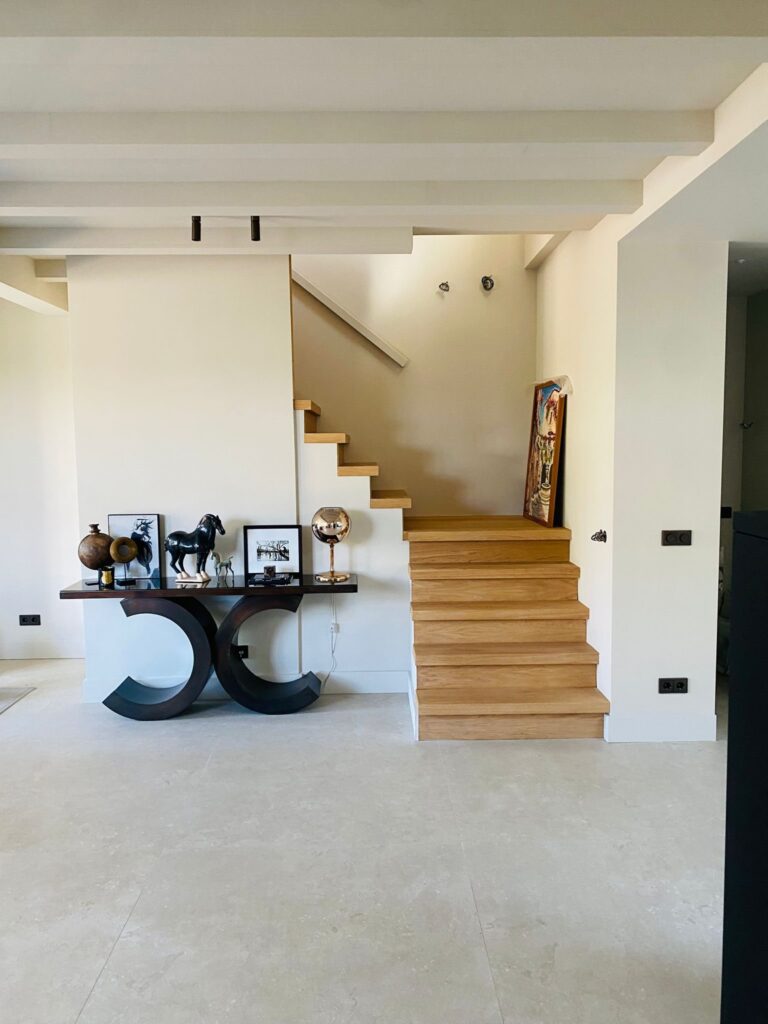 Eiken trap en een sidetable op een vloer van grote beige natuursteenlook tegels in Wassenaar