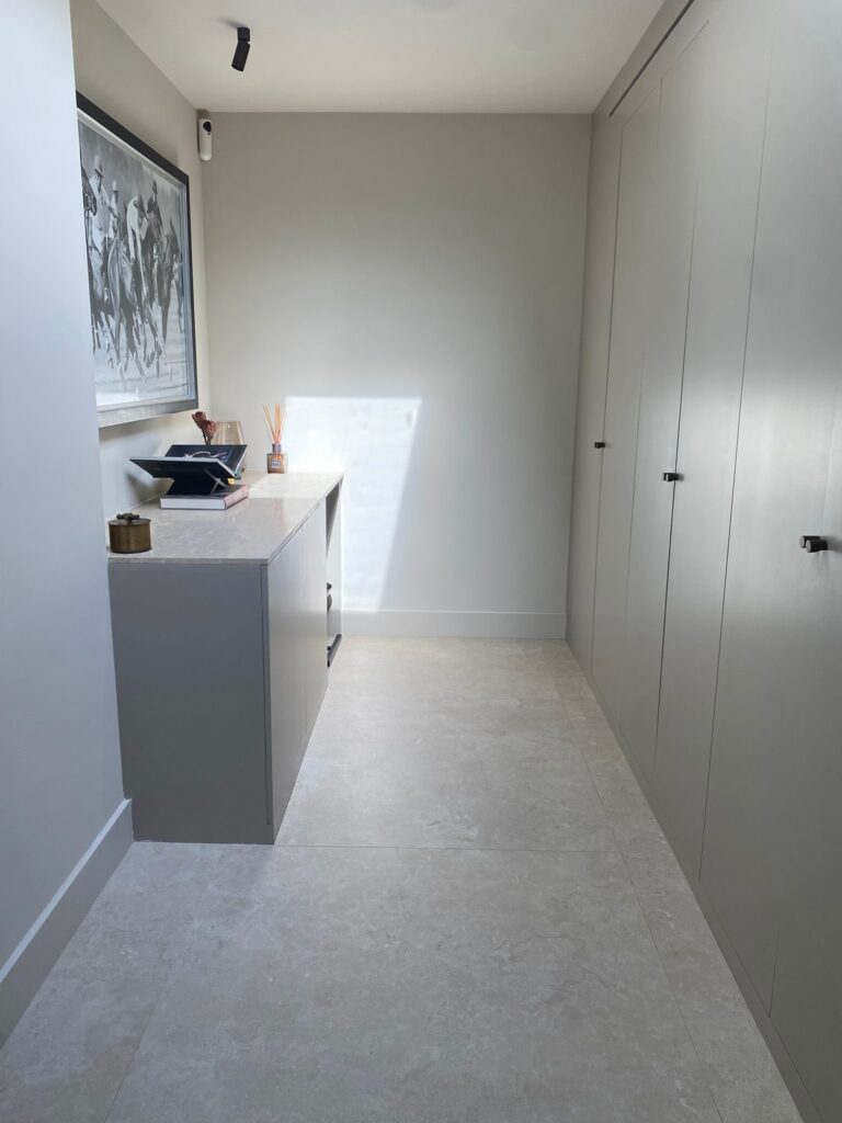 Gang met een kastenwand en een vloer van grote beige natuursteenlook tegels in Wassenaar
