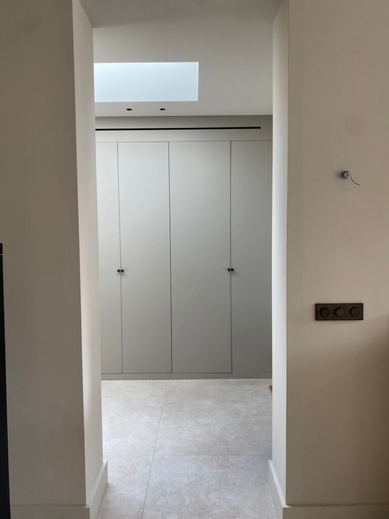 Doorkijk naar een kastenwand onder een daklicht, met beige natuursteenlook vloertegels van 120×120 in Wassenaar